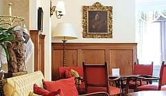 Intérieur de salon avec fauteuils rouges, canapé jaune, lampe sur pied et tableau doré