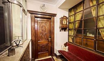 Entrée avec porte en bois sculpté, horloge à pendule et banc rouge