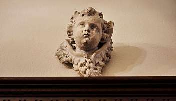 Sculpture en pierre d'une tête de chérubin accrochée à un mur au-dessus d'un cadre en bois