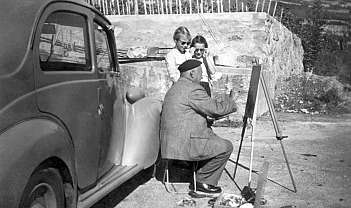 Homme âgé avec casquette peint sur un chevalet en plein air avec deux enfants qui observent