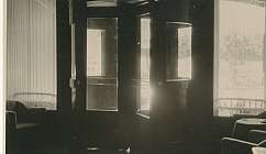 Intérieur avec porte tournante en bois et verre, chaises et table près des fenêtres