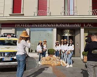 Groupe de femmes avec chapeaux et sacs photographiées devant l'Hotel International Au Lac