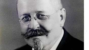 Primo piano di uomo anziano con occhiali, baffi e papillon in abito formale