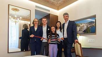 Cinque persone sorridenti in camera rinnovata durante una cerimonia di taglio del nastro