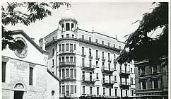 Place avec bâtiment historique à plusieurs étages et église en noir et blanc