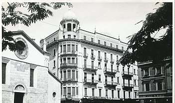 Place avec bâtiment historique à plusieurs étages et église en noir et blanc