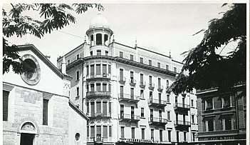 Place avec bâtiment historique à plusieurs étages et église en noir et blanc