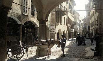 Rue pavée avec arches, homme en vêtements d'époque et cheval avec charrette