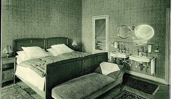 Chambre avec lit double, banc et deux lavabos avec miroirs