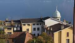 Bâtiments résidentiels avec toits rouges et jaunes devant un lac calme