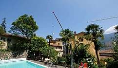 Piscine extérieure dans un jardin avec des arbres, des chaises orange et une grue en fonctionnement