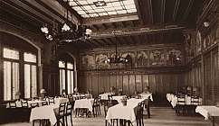 Intérieur d'une salle à manger historique avec des tables dressées et des lustres anciens