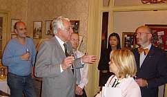 Groupe de personnes en tenue formelle et décontractée conversant dans une pièce avec des verres à la main