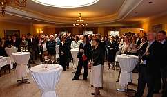 Personnes en tenue formelle dans une salle avec des tables hautes et des verres