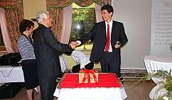 Deux hommes en costume se serrant la main lors d'un événement formel avec une femme en arrière-plan