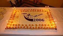 Gâteau rectangulaire décoré avec des bougies allumées pour célébrer 100 ans de 1906 à 2006