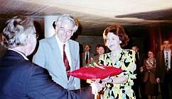 Femme recevant un paquet rouge d'un homme en veste avec des personnes en arrière-plan