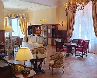 Salon élégant avec fauteuils, tables, lampes et bar en libre-service dans un environnement lumineux