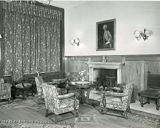 Salon d'époque avec cheminée en marbre, fauteuils rembourrés et table ronde