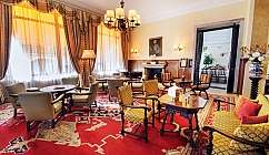 Salon classique avec fauteuils, tables, cheminée allumée et rideaux ornés