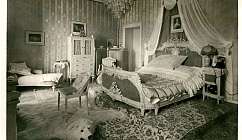 Chambre à coucher vintage avec lit décoré, fauteuil, tapis en peau d'ours et lustre