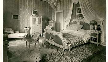 Chambre à coucher vintage avec lit décoré, fauteuil, tapis en peau d'ours et lustre