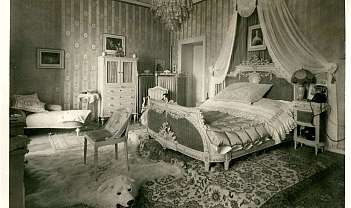 Chambre à coucher vintage avec lit décoré, fauteuil, tapis en peau d'ours et lustre