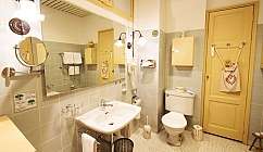 Salle de bain avec lavabo, grand miroir, WC, porte jaune et accessoires de salle de bain