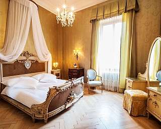 Chambre à coucher avec lit décoré, fauteuil, miroir ovale et sol en bois