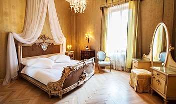 Chambre élégante avec lit décoré, fauteuil, miroir et lumière naturelle