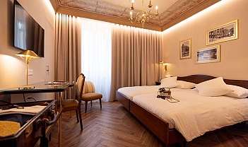 Chambre d'hôtel avec deux lits simples, parquet, lampes dorées et plafond décoré