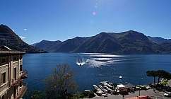 Vue panoramique d'un lac avec un bateau laissant une trace et des montagnes en arrière-plan