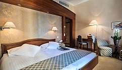 Chambre dh tel avec lit double, fauteuils, bureau et lampes murales