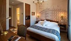 Chambre d'hôtel avec lit double, bureau, lampe dorée et mur décoré