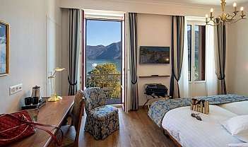 Chambre d h tel lumineuse avec deux lits, bureau, fauteuil et vue sur le lac et les montagnes