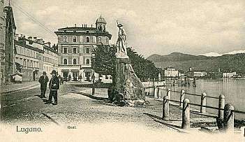 Vue historique du bord du lac de Lugano avec statue, personnes et montagnes en arrière-plan