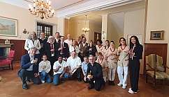 Groupe de personnes en tenue formelle et uniformes tenant des verres dans une pièce élégante