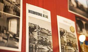 Affiches vintage d'hôtels accrochées à un mur rouge avec des images en noir et blanc