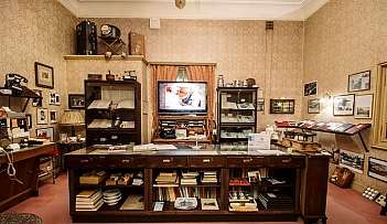 Salle de musée avec meubles anciens, livres, téléphones et objets d'époque exposés
