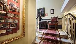 Escalier en marbre avec tapis rouge, fauteuil en bois et tableau accroché au mur