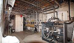 Local technique avec chaudières et tuyaux en métal au plafond et sur les murs