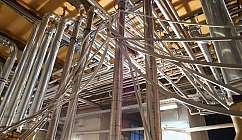 Vue en contre-plongée de tuyaux métalliques et câbles dans un environnement industriel