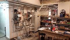 Local technique avec tuyauteries en métal, câbles électriques, étagères avec des boîtes et table de travail