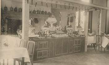 Buffet vintage avec des desserts décorés et des bouteilles suspendues dans la salle à manger