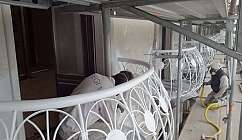 Deux ouvriers avec des masques de protection travaillent sur des balustrades de balcons blancs sur un chantier de construction