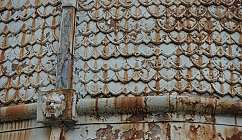 Détail d'un mur métallique avec peinture écaillée et rouille, décoration tête de lion