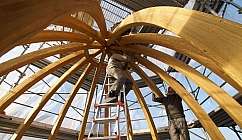 Deux ouvriers travaillent sur une structure en bois en forme de dôme avec des échafaudages autour