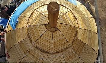Vue aérienne d'une coupole en bois en construction avec des panneaux et une colonne centrale
