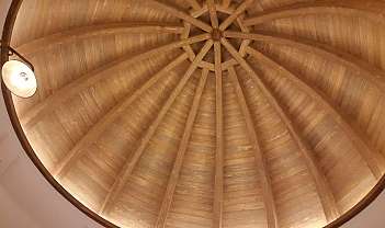 Vue intérieure d'un plafond en dôme réalisé avec des poutres et des panneaux en bois