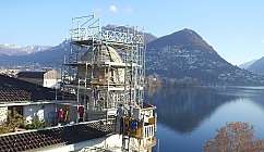 Travailleurs sur un échafaudage restaurent une coupole avec vue sur le lac et les montagnes en arrière-plan